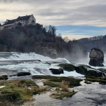 a castle on top of a hill next to a river