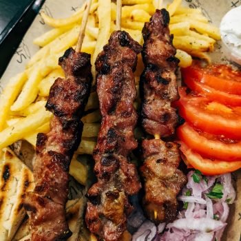 grilled meat with sliced tomato and green vegetable on white ceramic plate